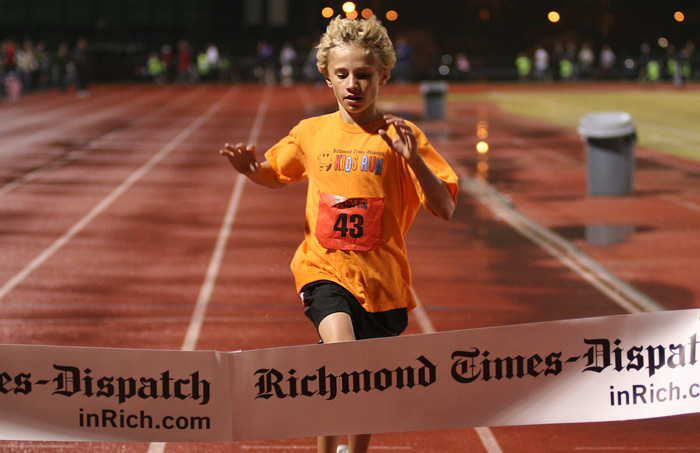 Twelve year-old Michael Correia from Chester, Virginia crosses the finish line first during Friday night�s Times-Dispatch Kids Run at the Sports Backers Stadium.  � Mike Lynaugh