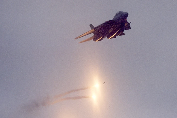 An F-14 Tomcat from VF-32 "The Swordsmen" pops flairs as he overflies the U.S.S. Enterprise out in the Atlantic Ocean.  � Mike Lynaugh