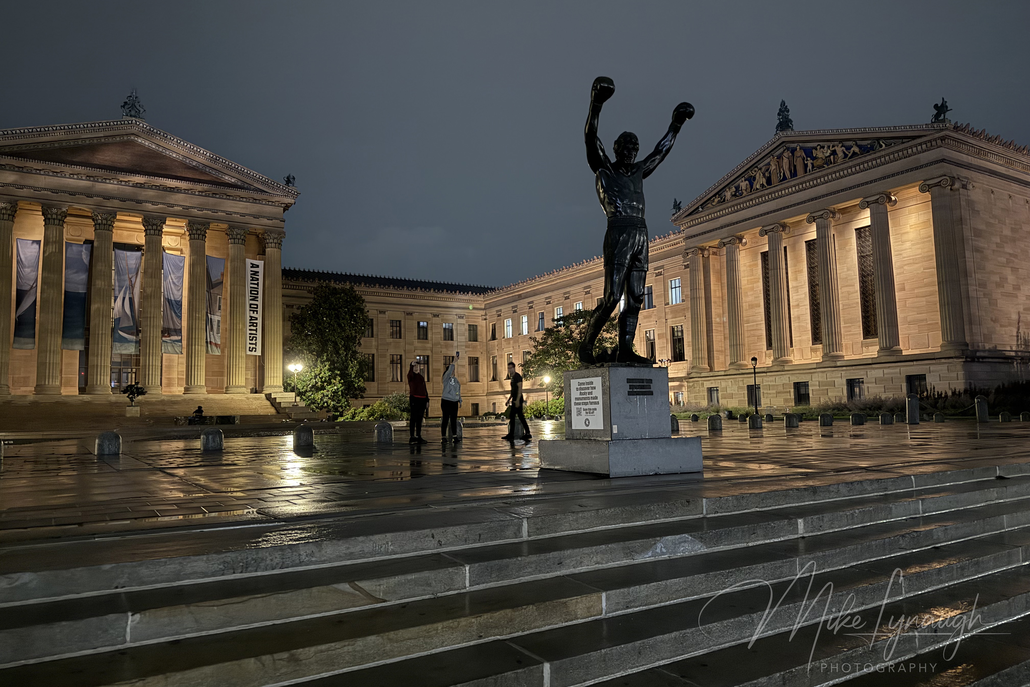 A wide angle view of the Rocky statue photographed during a rainy evening at the top of the Rocky Steps at the Philadelphia Museum of Art.