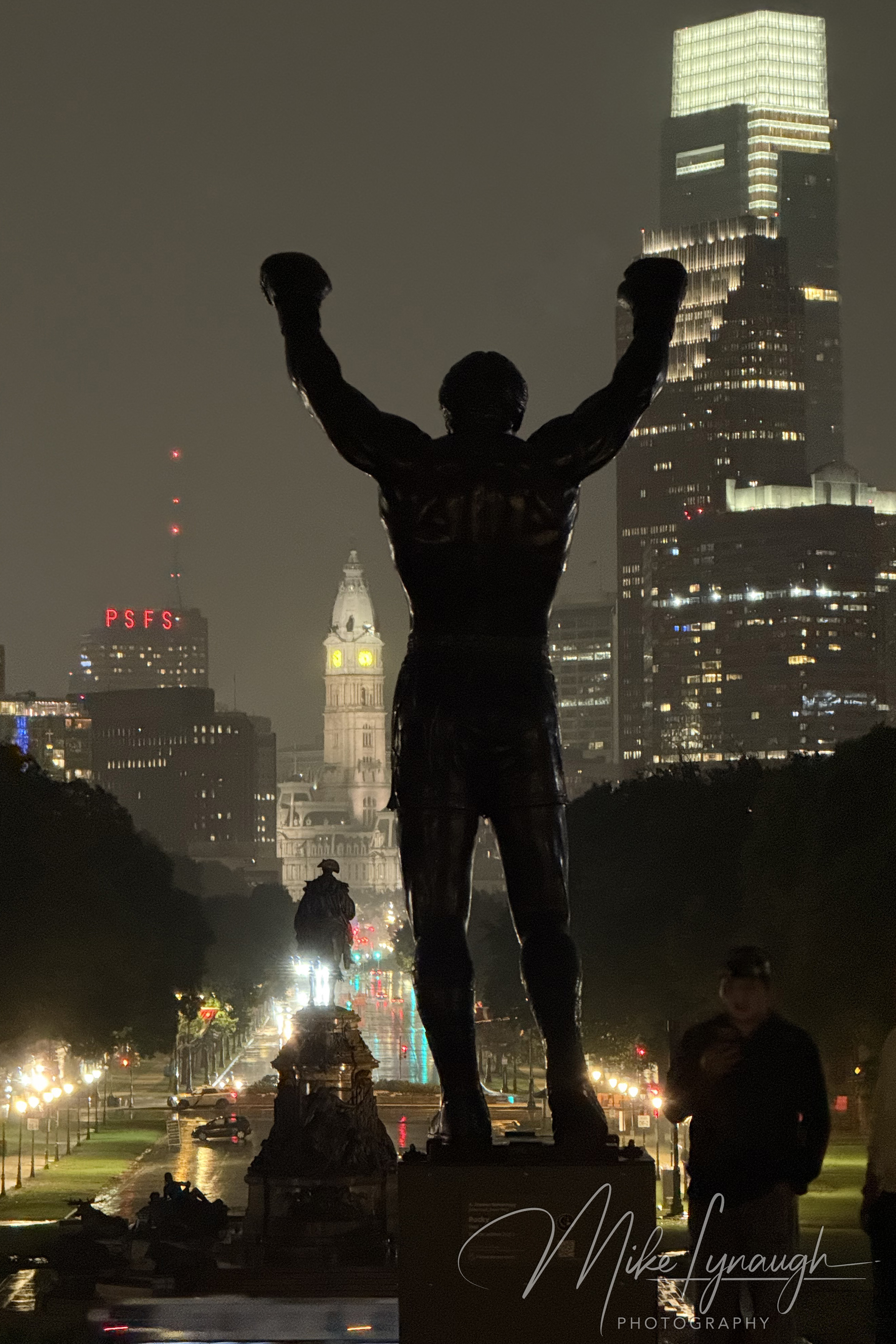 The Rocky statue photographed overlooking the Philadelphia skyline during a rainy evening at the top of the Rocky Steps at the Philadelphia Museum of Art.