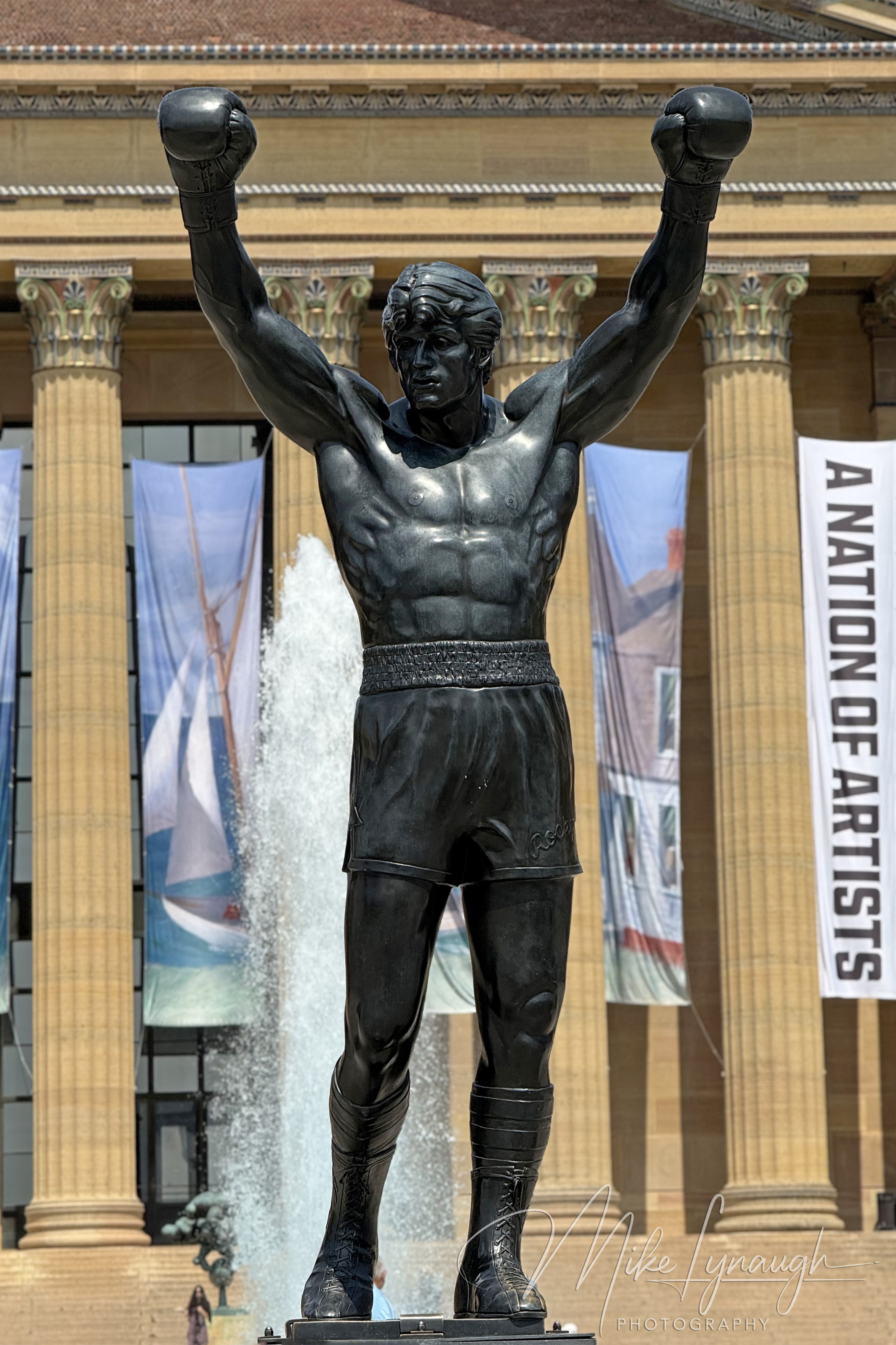 A vertical classic photo of the Rocky Statue at the top of the Rocky Steps at the Philadelphia Museum of Art.