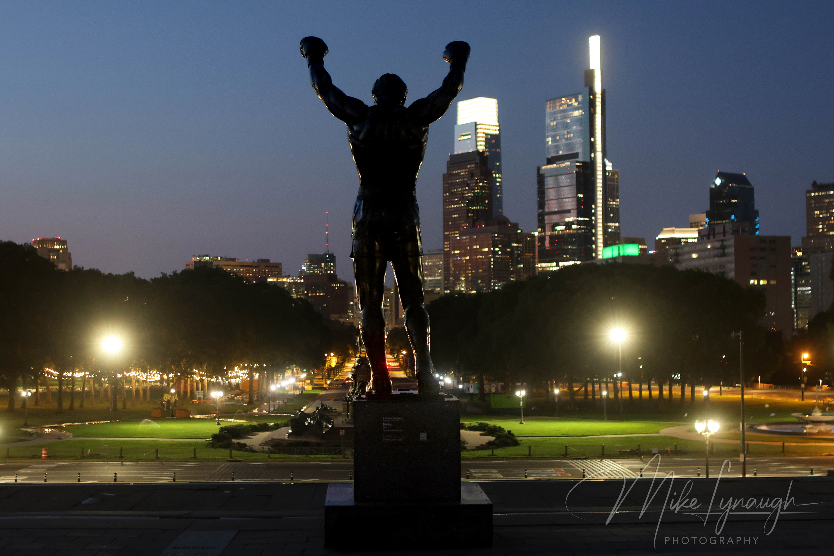 Rocky Statue — Overlooking the Skyline at night. The Rocky statue photographed at the start of sunrise as it overlooks the Philadelphia skyline from the top of the Rocky Steps.