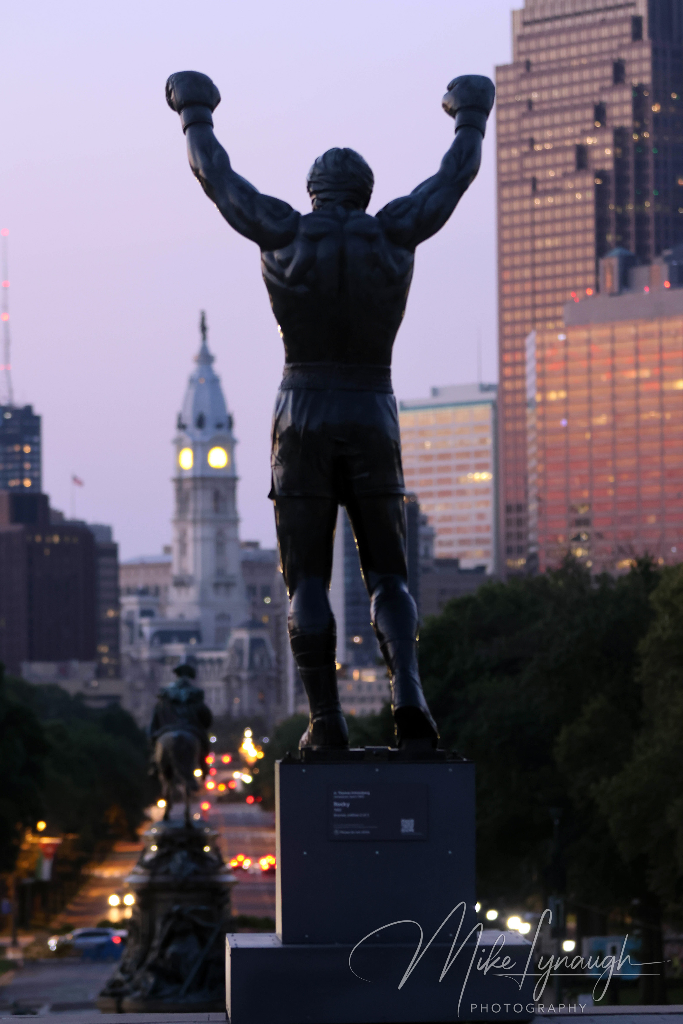 Rocky Statue — Sunrise at the Philadelphia Museum of Art and Skyline. A vertical image of Sylvester Stallone's personal Rocky Statue overlooks the Philadelphia skyline as the morning light begins to illuminate the city.
