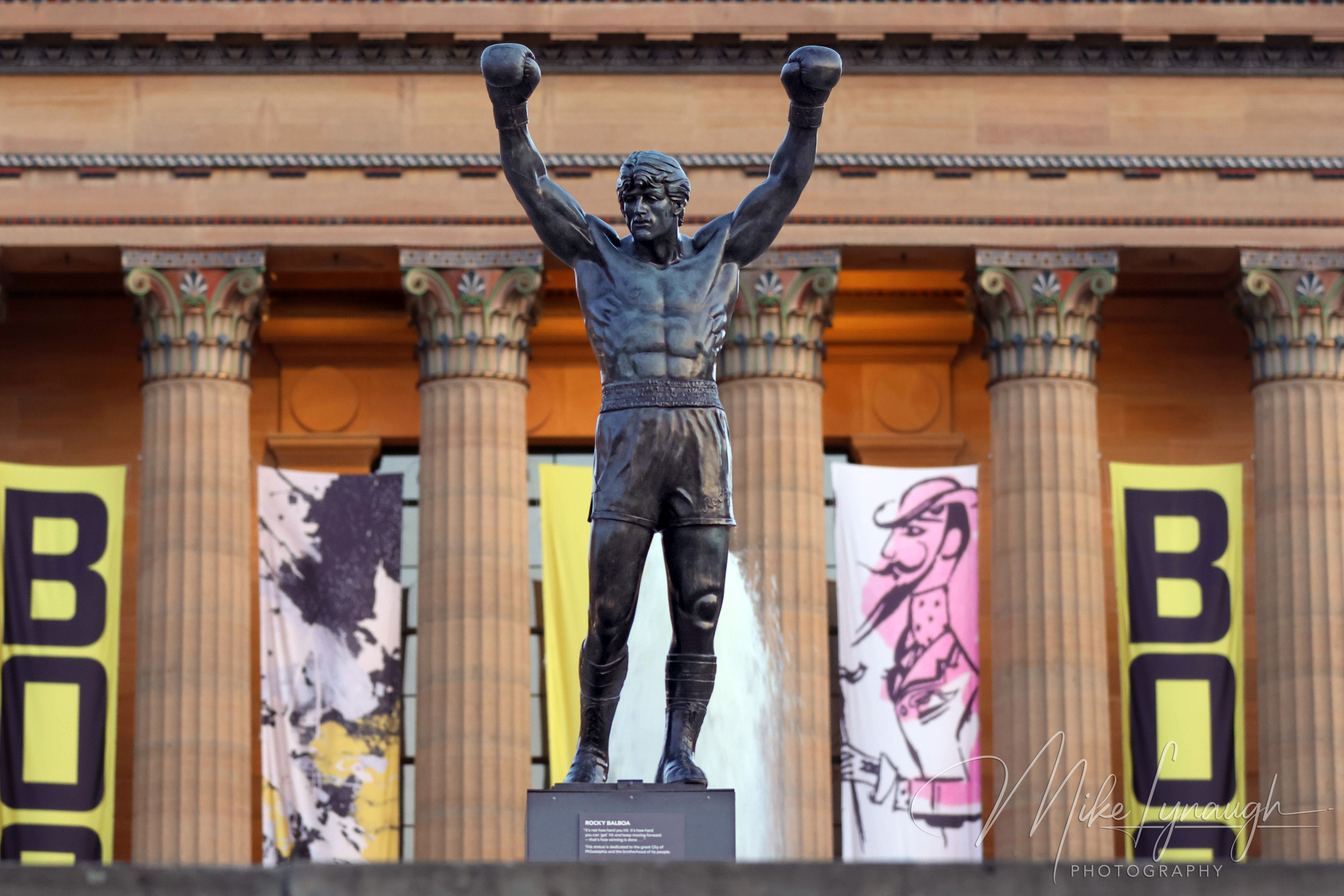 The Rocky statue photographed in front of the main entrance to the Philadelphia Museum of Art at the top of the iconic Rocky Steps.