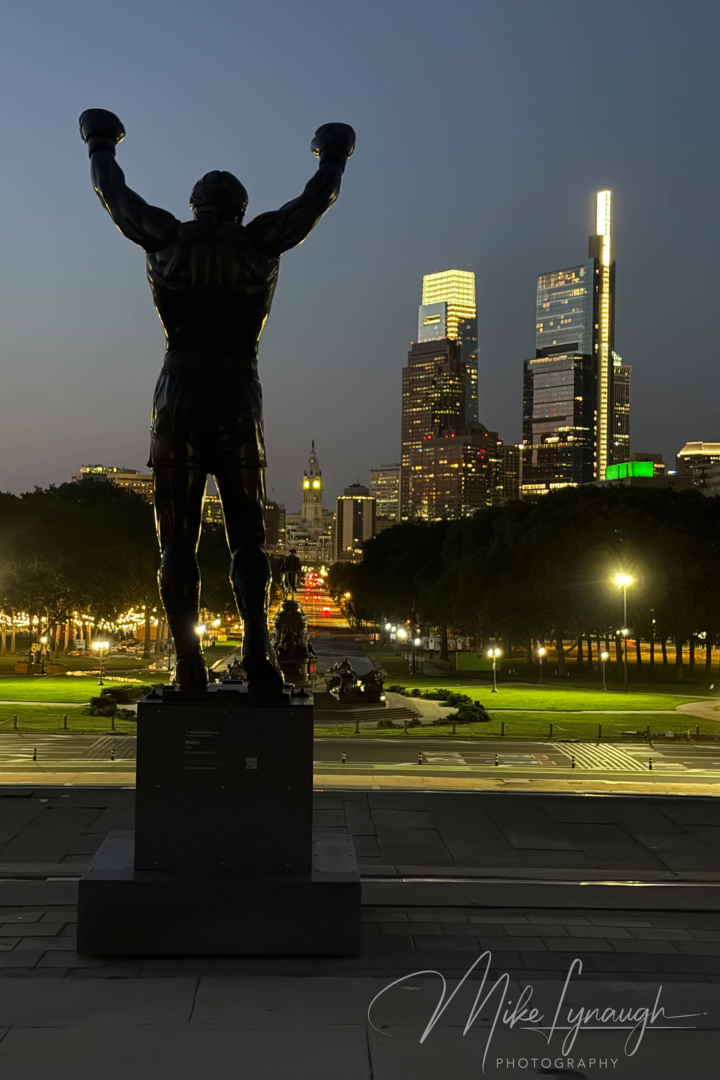 Rocky Statue — Overlooking the Philadelphia Skyline at night. The Rocky statue photographed at the start of sunrise as it overlooks the Philadelphia skyline from the top of the Rocky Steps.