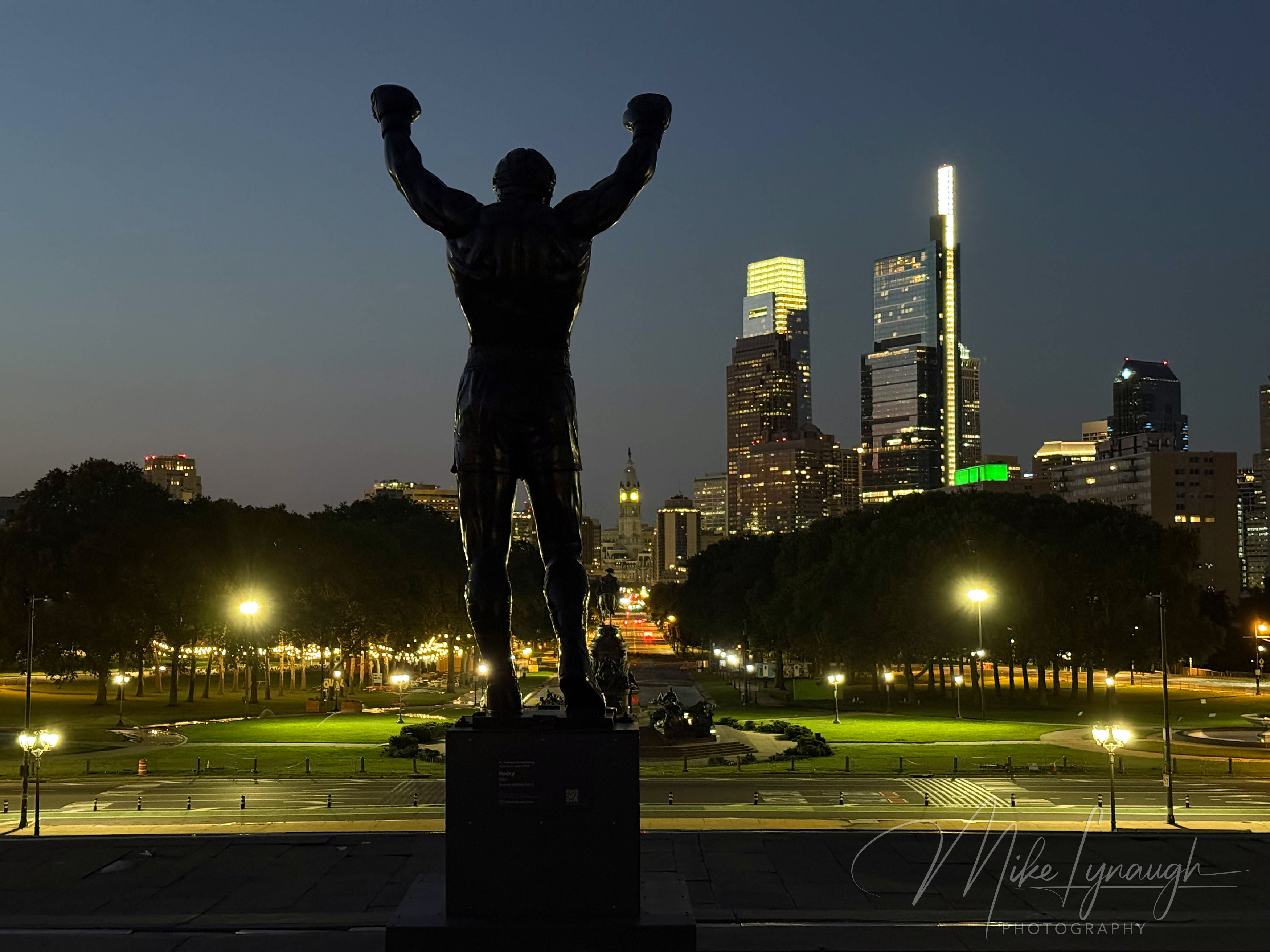 Rocky Statue — Overlooking the Philadelphia Skyline at night. The Rocky statue photographed at the start of sunrise as it overlooks the Philadelphia skyline from the top of the Rocky Steps.