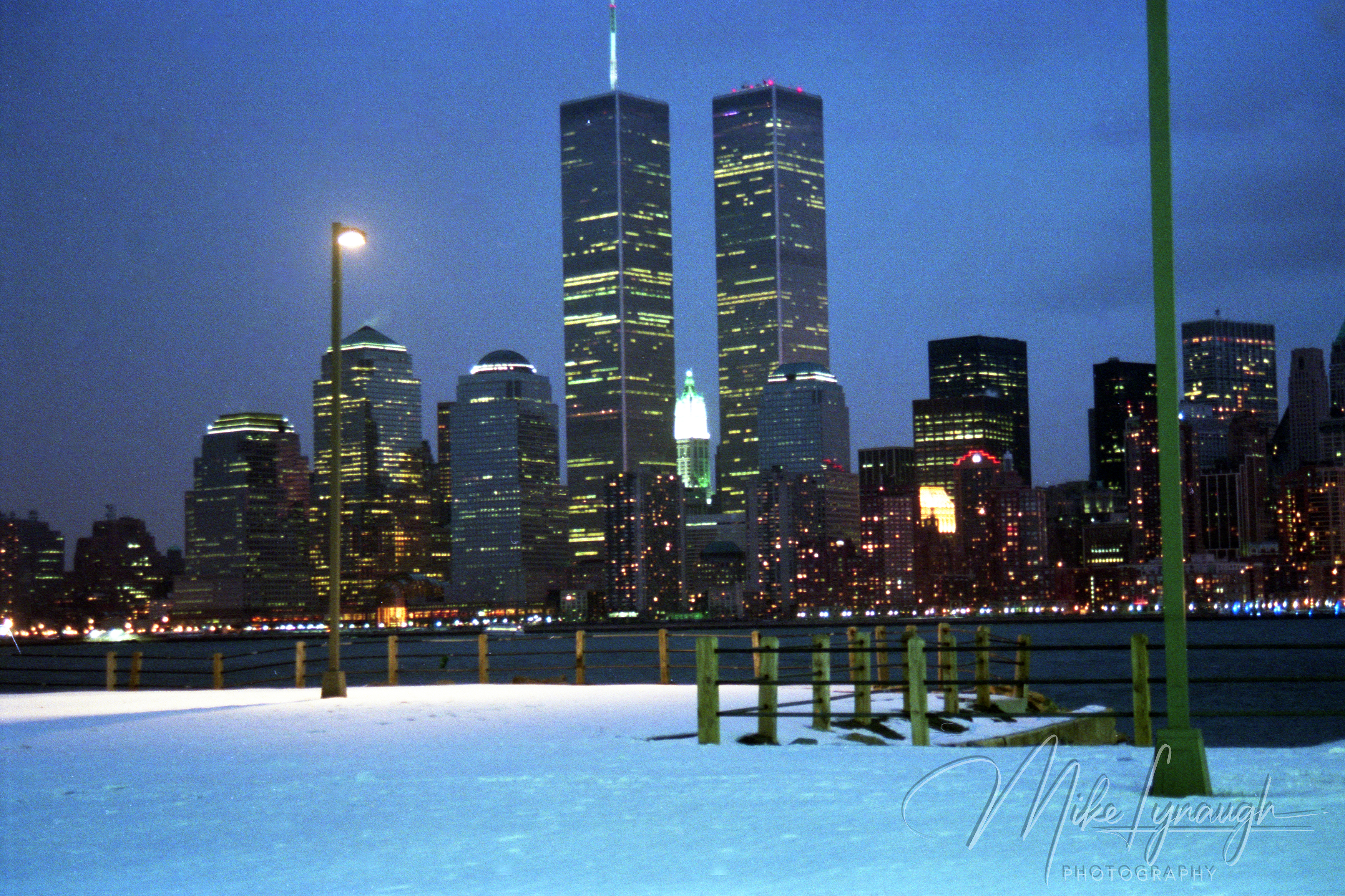 Illuminated World Trade Center Twin Towers and Lower Manhattan skyline across a snow-covered park in March 1992