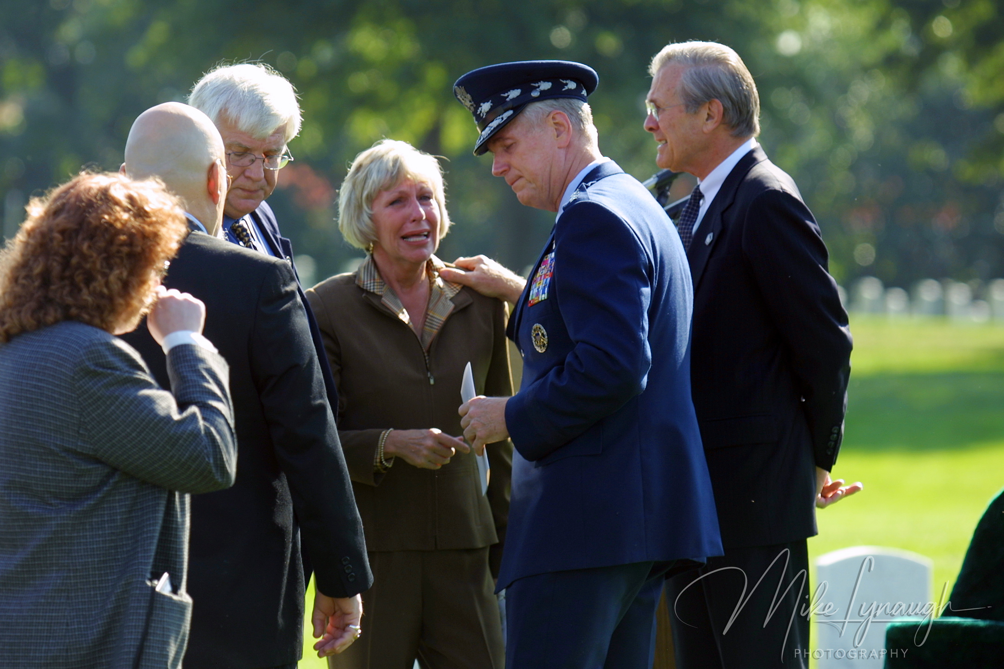 General Richard Myers leaning in to comfort a tearful woman while Secretary Donald Rumsfeld stands nearby at Arlington National Cemetery