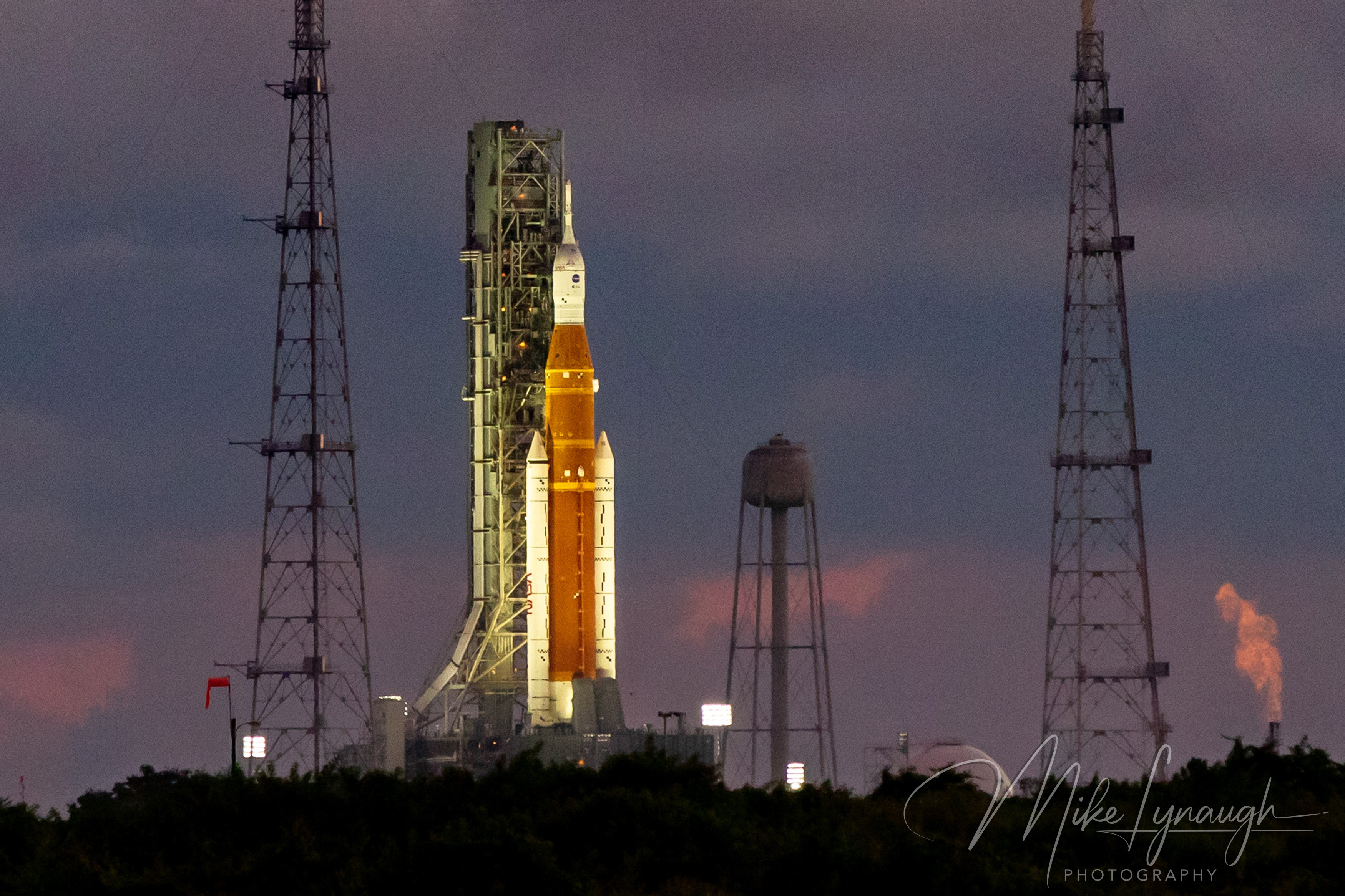 A photograph captured from the NASA Press Site highlighting the Space Launch System (SLS) rocket and Orion spacecraft on Launch Pad 39B at sunrise.