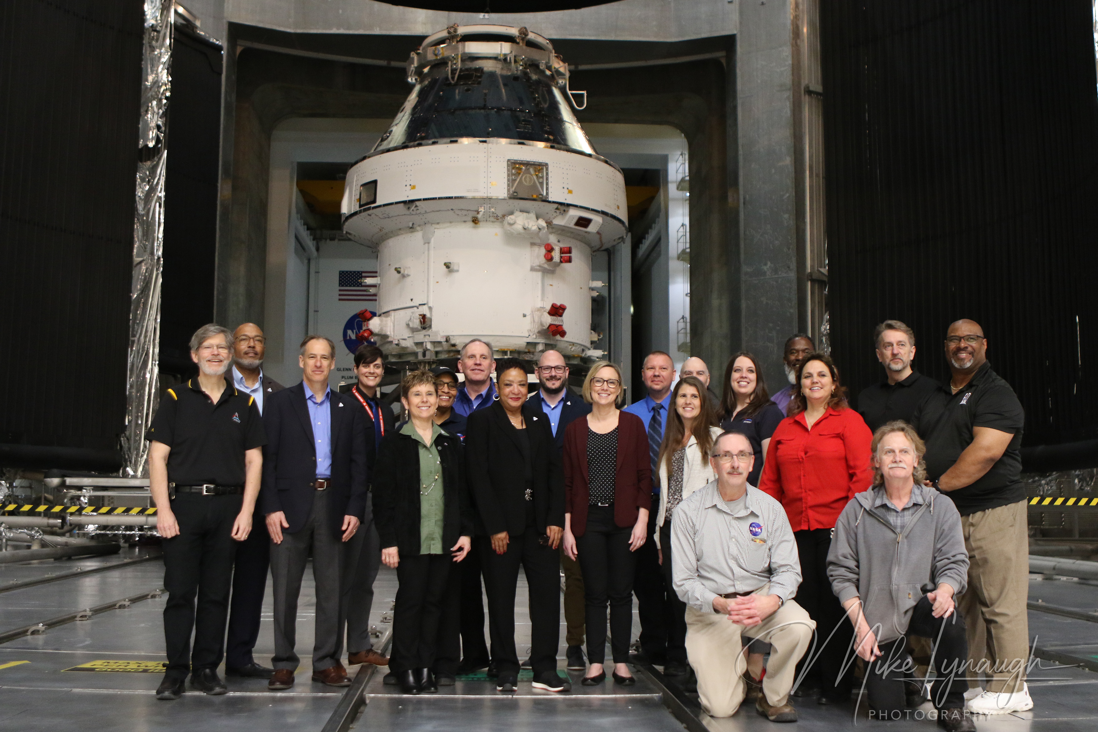 A wide interior group photograph showing NASA personnel, engineers, and media representatives posed directly in front of the Artemis I Orion spacecraft stack.